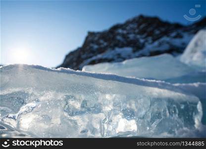 The icy beauty of ice cube, unusual shapes. Closeup crystal clear ice cube that covered with white snow. Lake Baikal, Russia