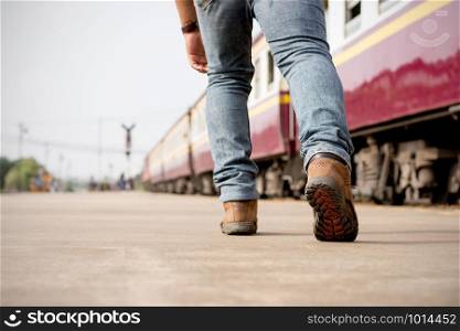 The image behind the legs of a male tourist walking near the railway station.