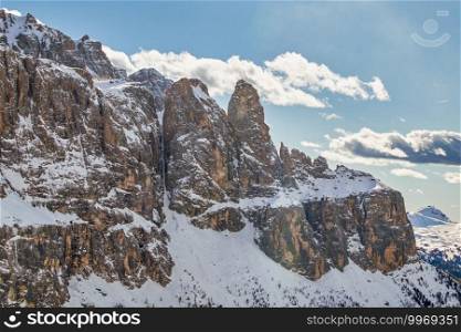 the impressive snow-covered rock formation called sella towers in the dolomites in south tyrol in italy in winter with a blue cloudy sky. Rock formation called sella towers in the dolomites in south tyrol in winter