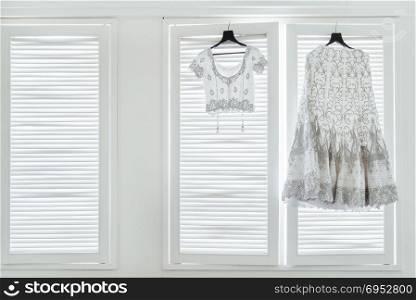 The indian wedding dress, saree and blouse hanging with the white windows with light in background.. Indian Wedding Dress and Blouse hanging on the windows