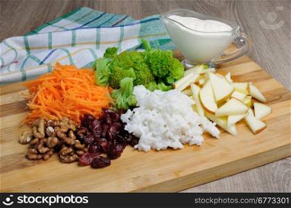 The ingredients are laid out on a wooden board for salads