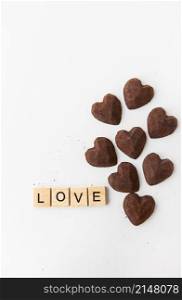 The inscription in wooden letters love, small truffle candies in the form of a heart. The inscription in wooden letters love, small truffle candies in the form of a heart.