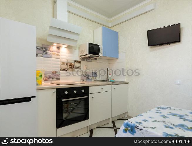 The interior of a small kitchen with a TV on the wall