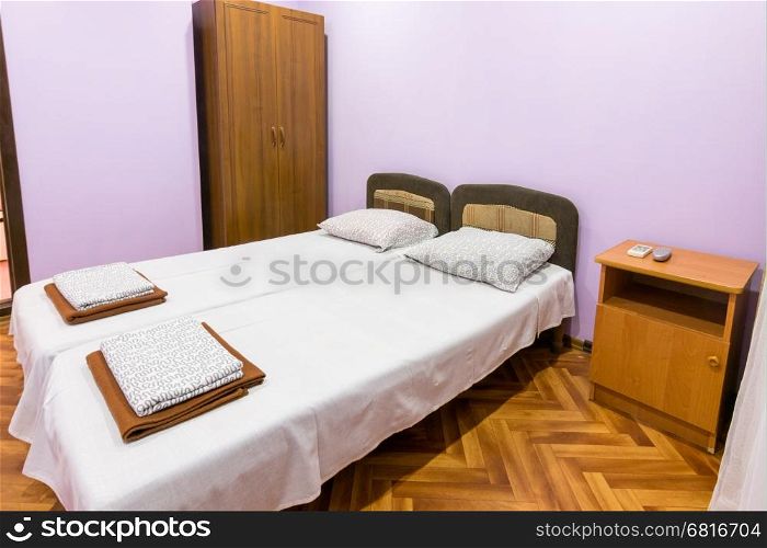 The interior of a small room with a double bed, a bedside table and wardrobe