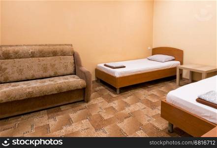 The interior of a small room with a sofa and two beds