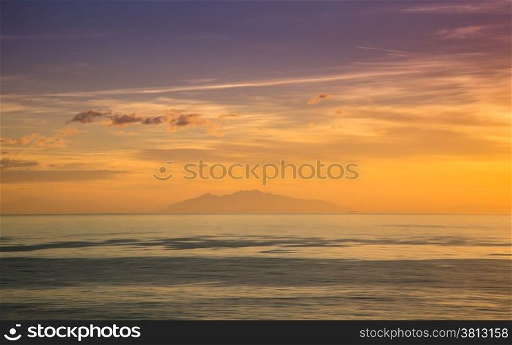 The island of Elba silhouetted against an orange and purple dawn sky