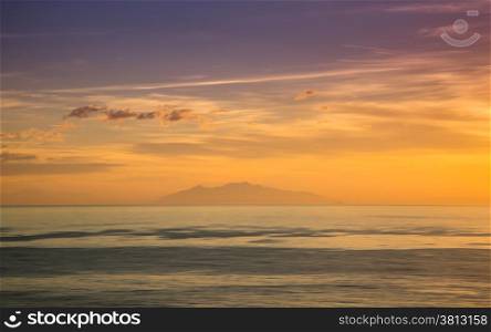 The island of Elba silhouetted against an orange and purple dawn sky