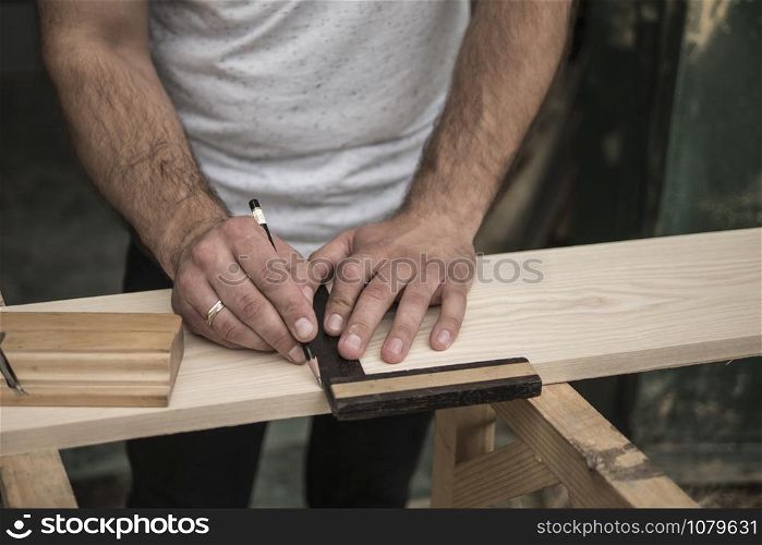 The joiner marks the workpiece with a pencil. joinery. carpenter. woodworker