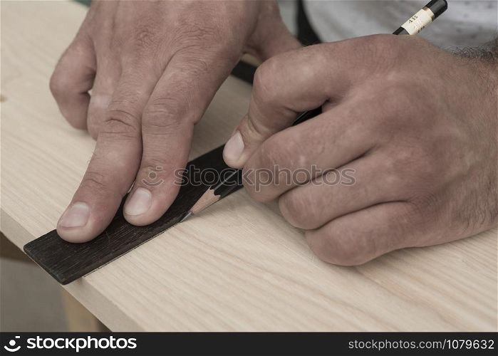 The joiner marks the workpiece with a pencil. joinery. carpenter. woodworker