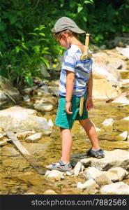 The kid plays near a mountain stream
