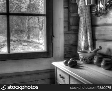 The kitchen inside a wooden cottage, tomatoes on the table, black and white image