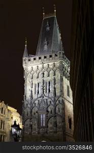 The landmark Powder Tower on the edge of the Old Town of Prague is illuminated at night with a spotlight.