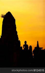 The landscape of the ancient Buddhist temple of Wat Chaiwatthanaram at dusk, the ancient Buddha statue, and the pagoda against the sunset sky. Ayutthaya Historical Park, Thailand.