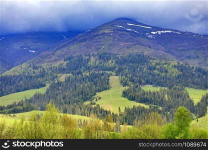 The landscape of the Carpathian mountains whose peaks are shrouded in dense fog in early spring.. The landscape of the majestic mountain in the Carpathians along the slope of which the cable lift is laid.