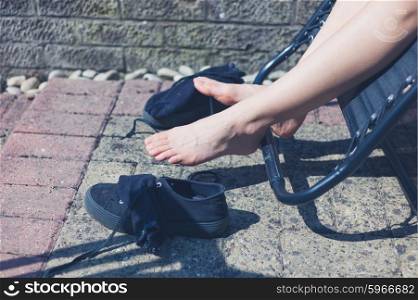 The legs and feet of a woman outside as she is relaxing on a sun lounger