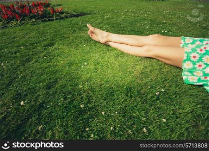 The legs of a beautiful young woman as she is lying on the grass in a park