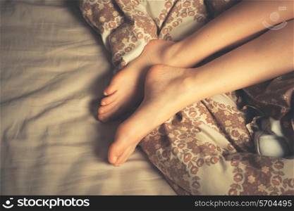The legs of a beautiful young woman as she lies in bed