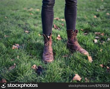 The legs of a person wearing boots and standing on the grass