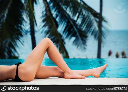 The legs of a sexy young woman relaxing by the pool