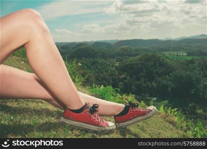 The legs of a young woman as she is relaxing on a hill in the tropics