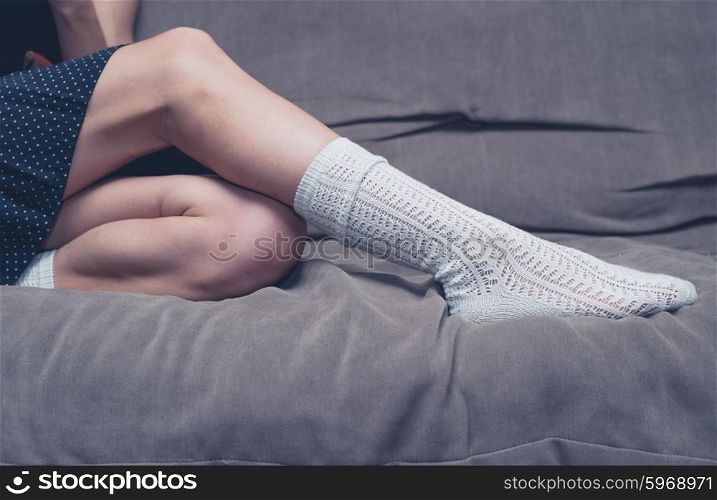 The legs of a young woman as she is relaxing on a sofa