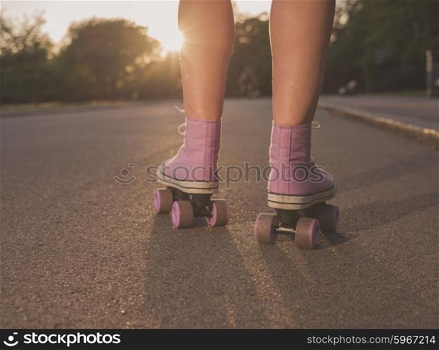 The legs of a young woman as she is roller skating in a park at sunset