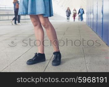 The legs of a young woman as she is walking in a station or terminal