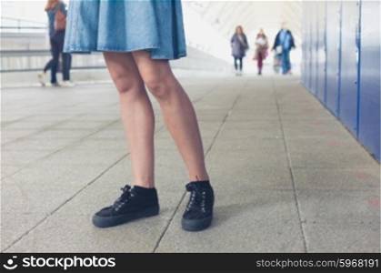 The legs of a young woman as she is walking in a station or terminal