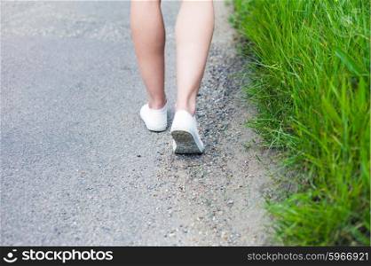 The legs of a young woman as she is walking on a road in the country