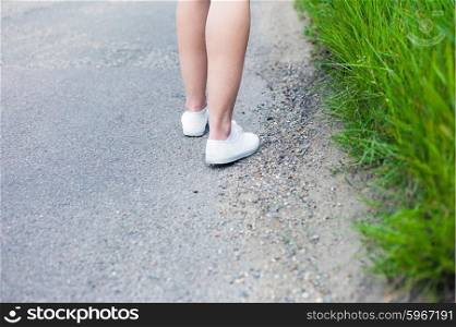 The legs of a young woman as she is walking on a road in the country