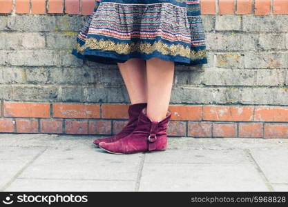 The legs of a young woman wearing a colorful skirt as she is standing in the street