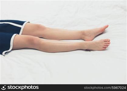 The legs of an elegant young woman lying on a bed