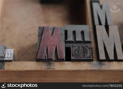 the letter M in different sizes and fonts in a wood type case