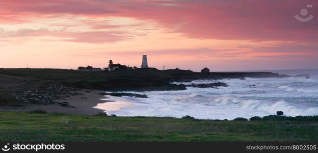 The lighthouse shines light out to the sea at sunrise