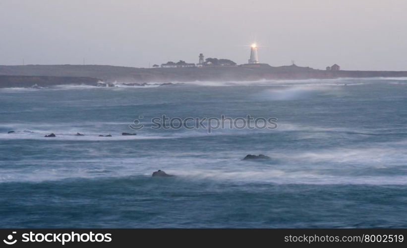 The lighthouse shines light out to the sea at sunrise