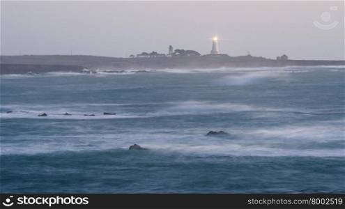 The lighthouse shines light out to the sea at sunrise