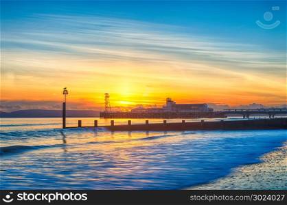 The lights of Bournemouth Pier at night reflected in the wet sand on the beach. Dorset England UK Europe.