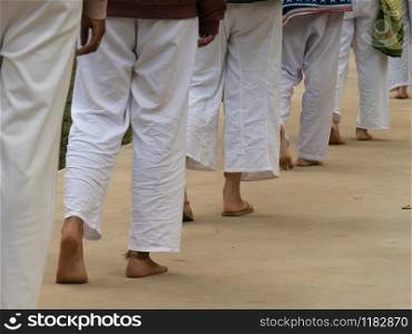 The line of people feet walking meditation and all in white clothes.