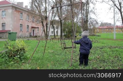The little boy is swinging an old swing.