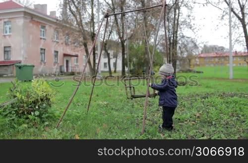 The little boy is swinging an old swing. Johvi, Estonia.