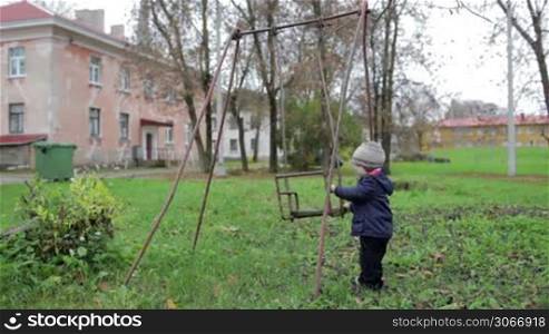 The little boy is swinging an old swing. Johvi, Estonia.