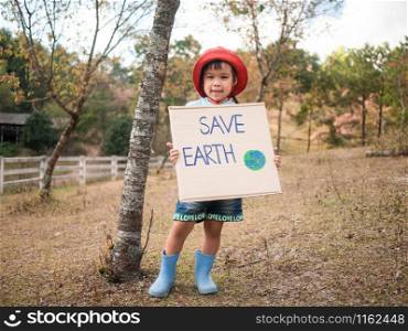 "The little child girl holding "Save The Earth" Poster showing a sign protesting against plastic pollution in the forest. The concept of World Environment Day. Zero waste."