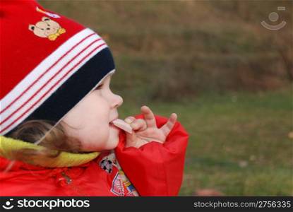 The little girl eating sausage (ham) on the nature