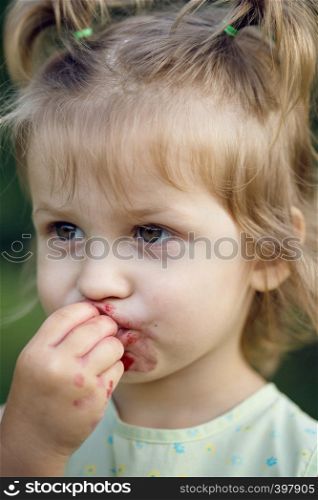 the little girl eats cherry in the garden. Summer