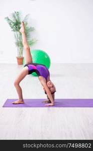 The little girl gymnast doing exercises indoors. Little girl gymnast doing exercises indoors