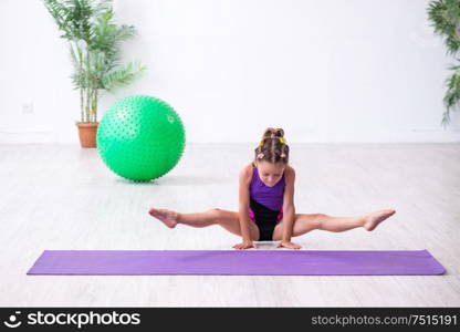 The little girl gymnast doing exercises indoors. Little girl gymnast doing exercises indoors
