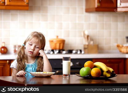 The little girl looks at a plate with a breakfast on kitchen