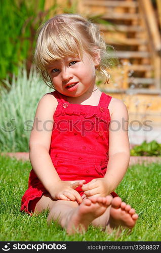 The little girl sits on a lawn