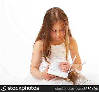 The little girl with long hair sits and reads the book
