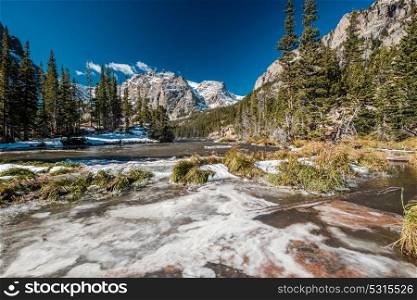 The Loch Lake with rocks and mountains in snow around at autumn. Rocky Mountain National Park in Colorado, USA.